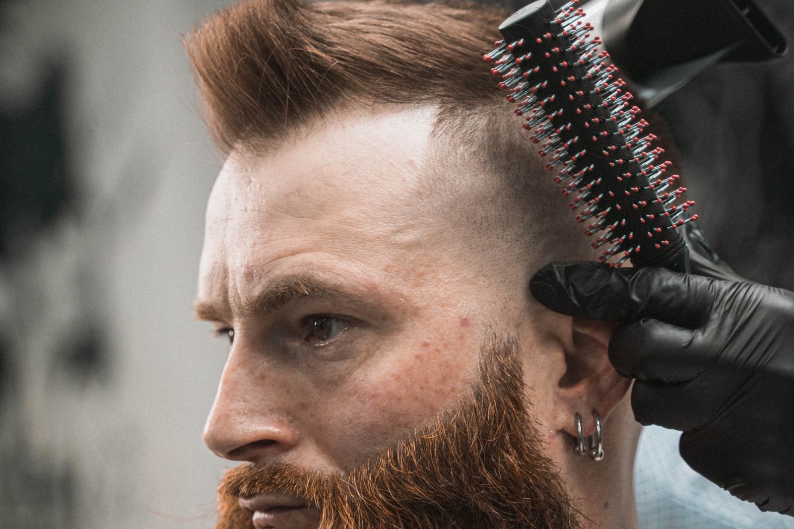 Bearded man getting his hair styled by a barber, men's haircut trends fall 2026