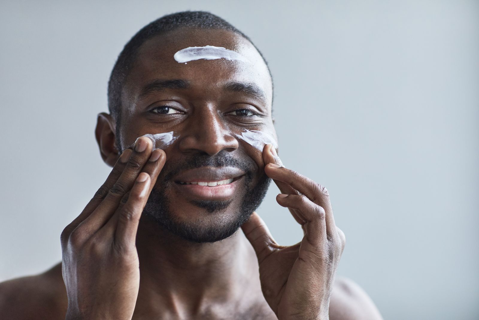 Bearded man applying face cream as part of his men's winter skin care routine