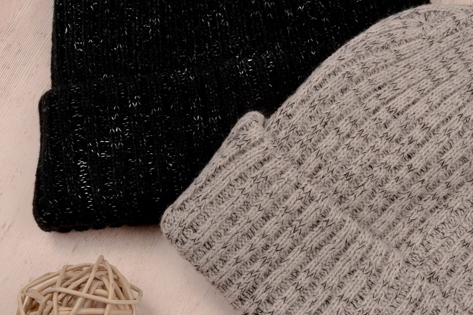 Beanie vs. hat guide: a black and a grey ribbed knit beanie on a light wooden surface