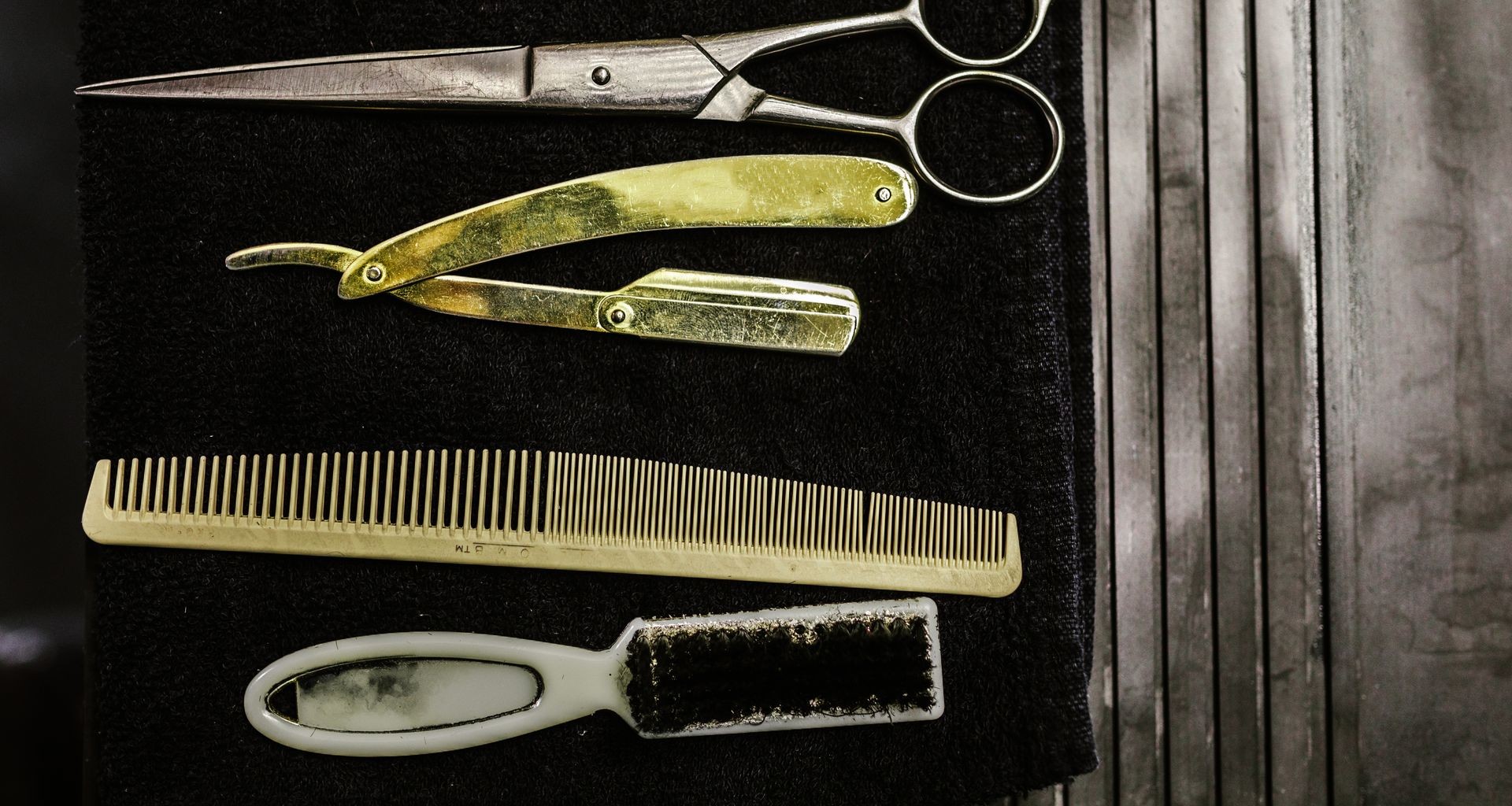 Vintage barber tools, scissors, straight razor, comb and brush on a dark towel, for a guide to men's hair loss treatments 2026