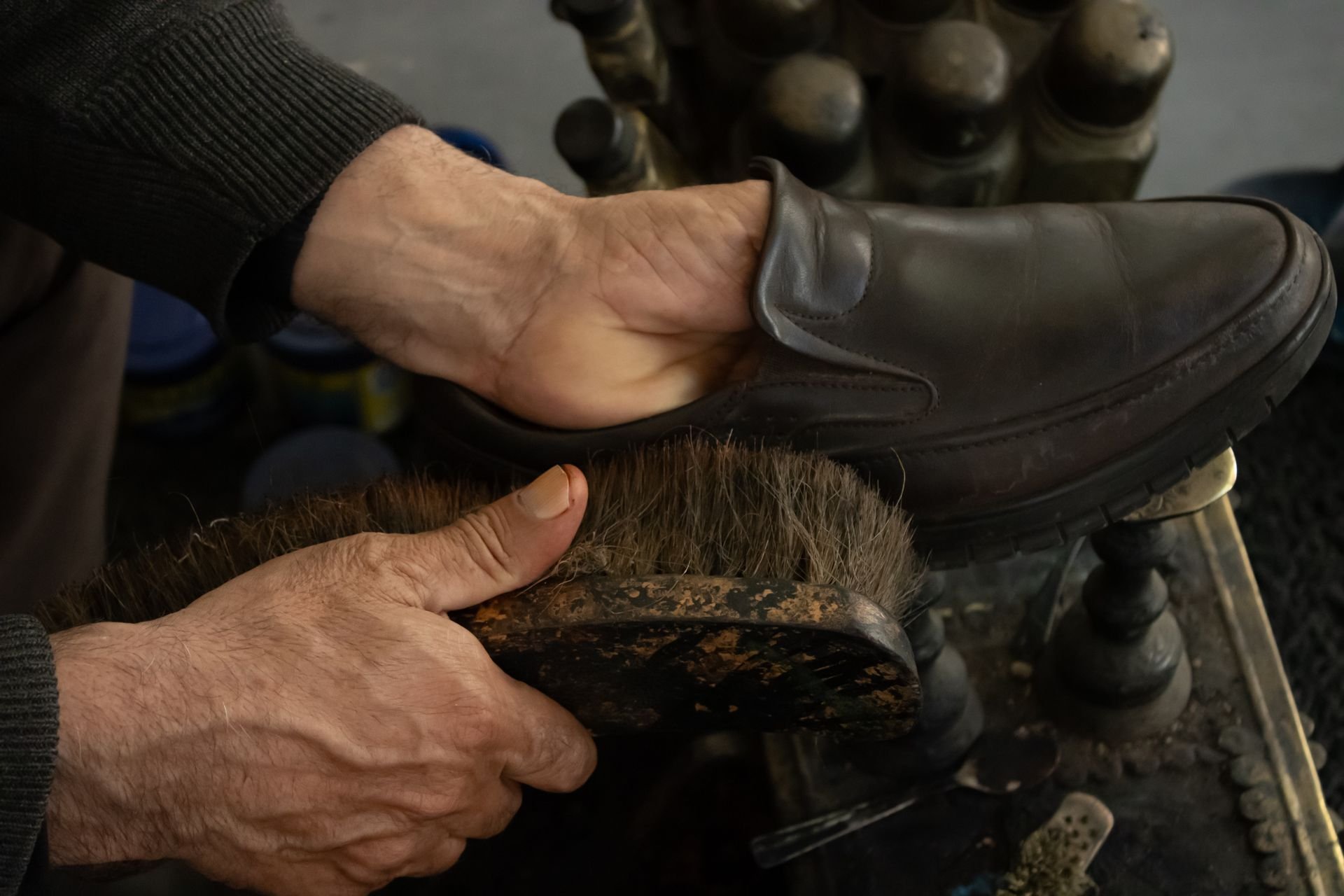 Winter shoe care: a horsehair brush polishing a dark leather loafer at a traditional shoe shine stand